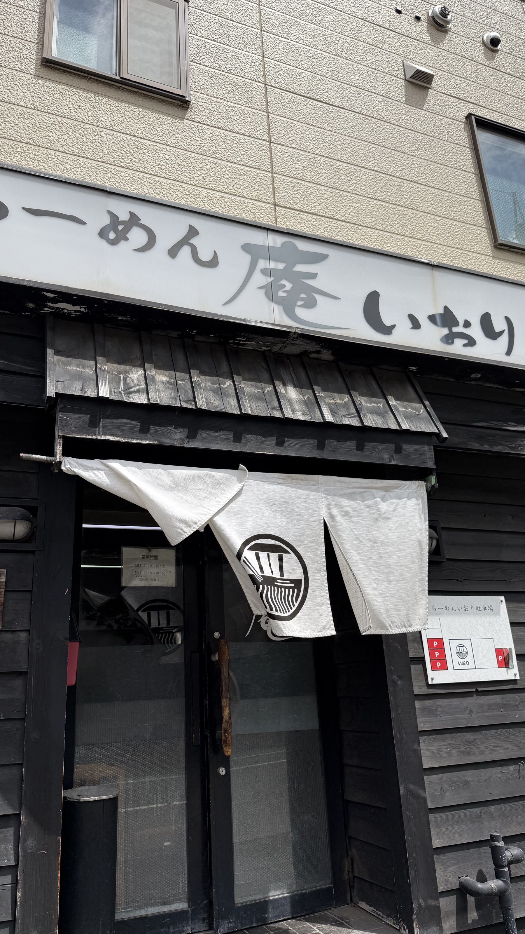 らーめん庵 いおりの外観。黒い木調の店構えに「らーめん庵 いおり」の看板、丼マークの白い暖簾がかかる