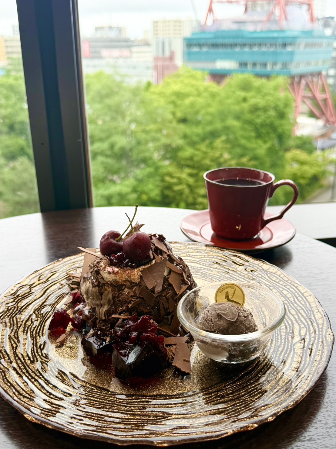 café KANONの季節限定フォレノワール風パンケーキ。チョコレートシェイブとチェリーで覆われ、チョコレートアイスと紅茶が添えられている