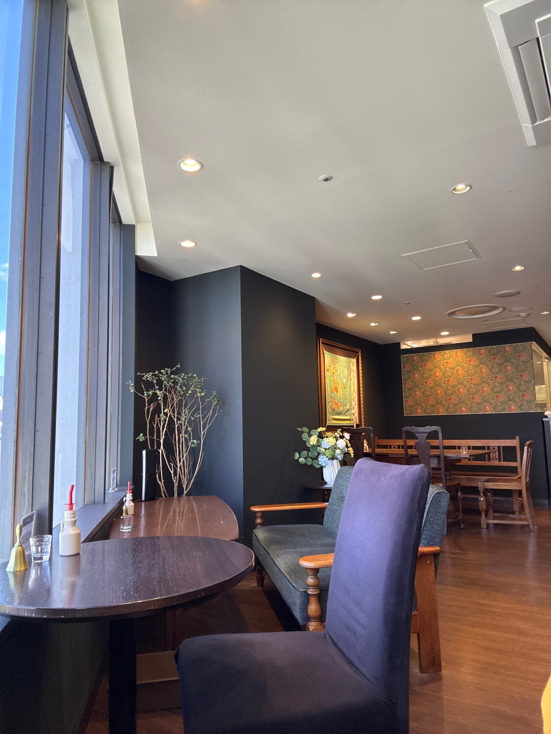 café KANONの店内。深い色味の壁にモリス調のテキスタイル、木のテーブルとアンティーク調の椅子が並ぶ