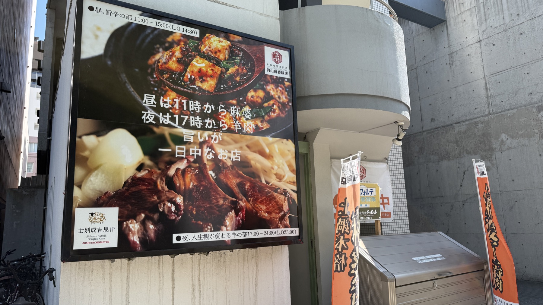 円山麻婆飯店の店外大型看板。麻婆豆腐とジンギスカン（羊の塊肉）の写真が上下に並び、キャッチコピー「昼は11時から麻痺感、夜は17時から羊腩。旨いが一日中なお店」。横には「士別咸吉惠汁」と書かれた朱色の幟