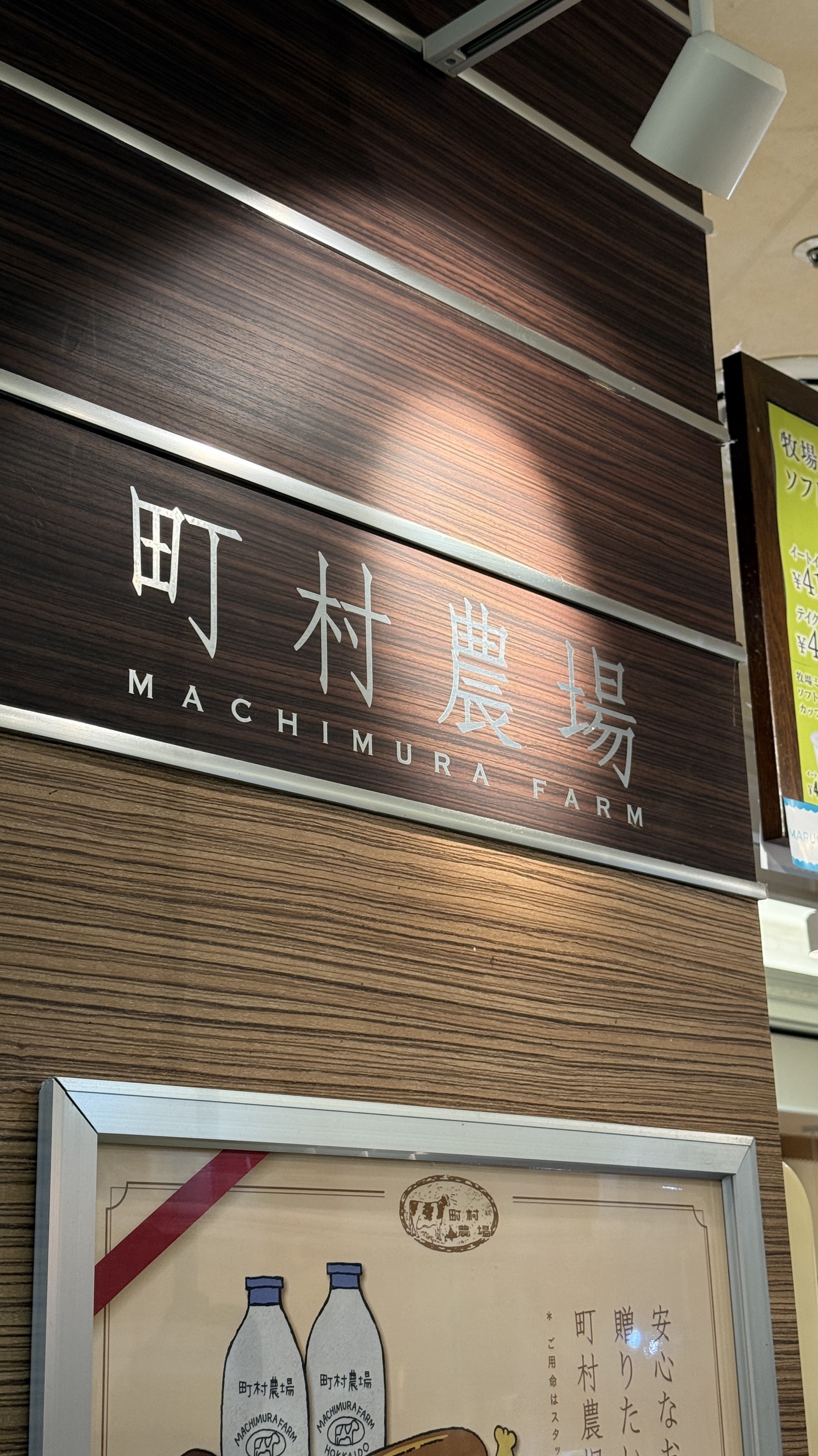 「町村農場 MACHIMURA FARM」の店舗看板。木目の壁に白い文字