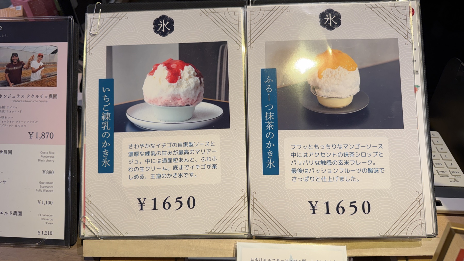 丸美珈琲店のかき氷メニュー表。「いちご練乳のかき氷 ¥1650」と「ふるーつ抹茶のかき氷 ¥1650」が並ぶ。クリップで留められたメニューブックの一枚