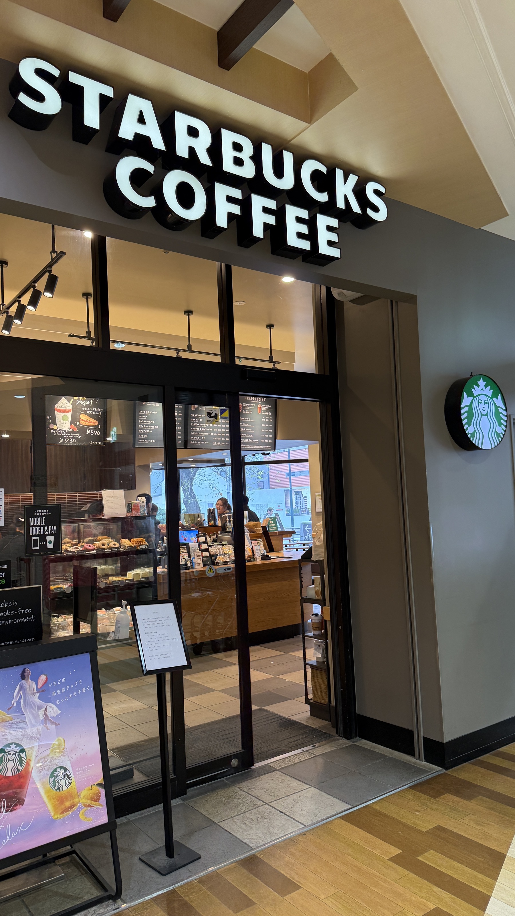 マルヤマクラス1階のスターバックス入口。STARBUCKS COFFEE のサイン、その横に丸いロゴ