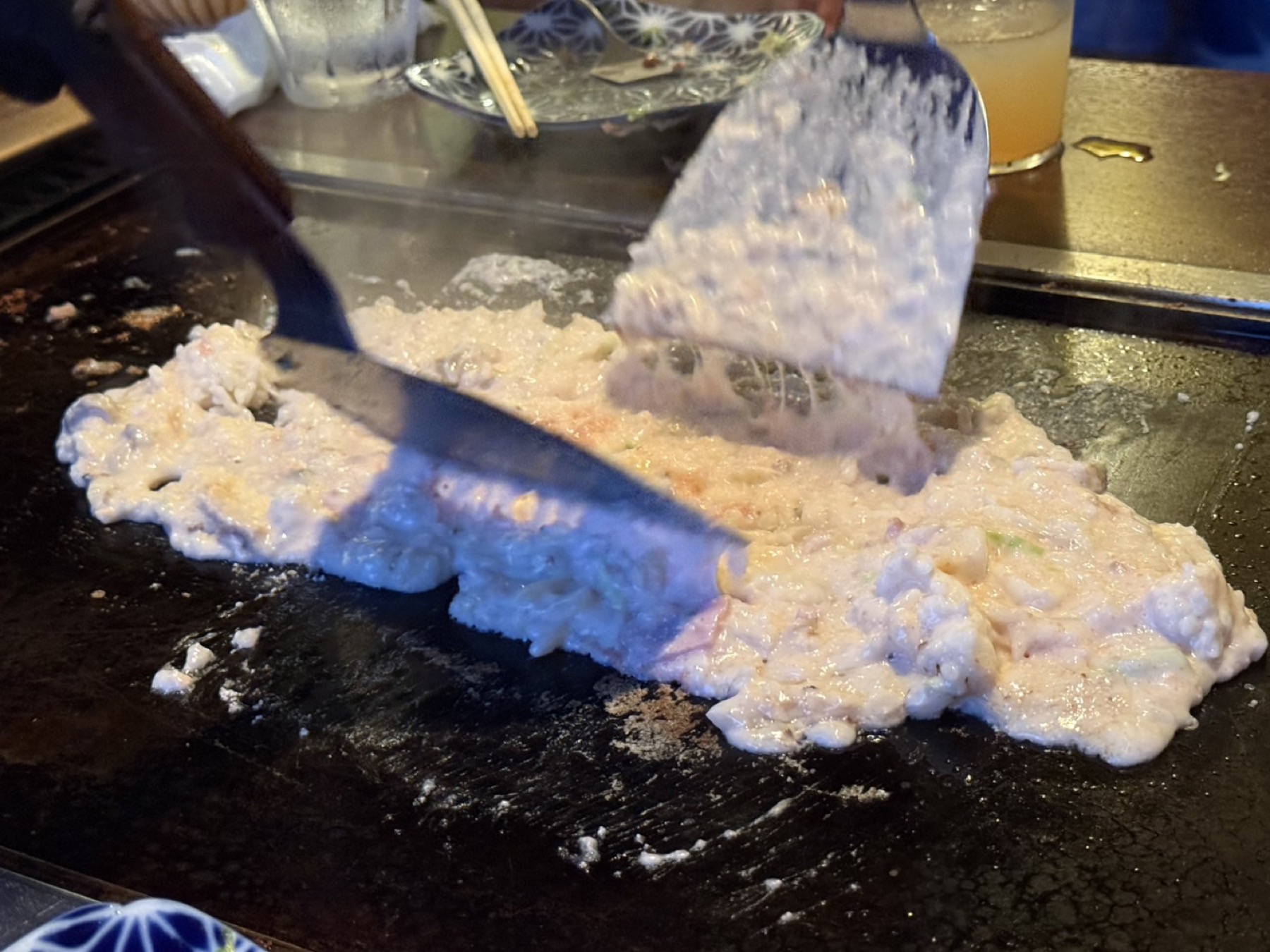 鉄板の上でヘラを使って焼き上げられるリゾット。米粒が見える生地がヘラで平らにならされている