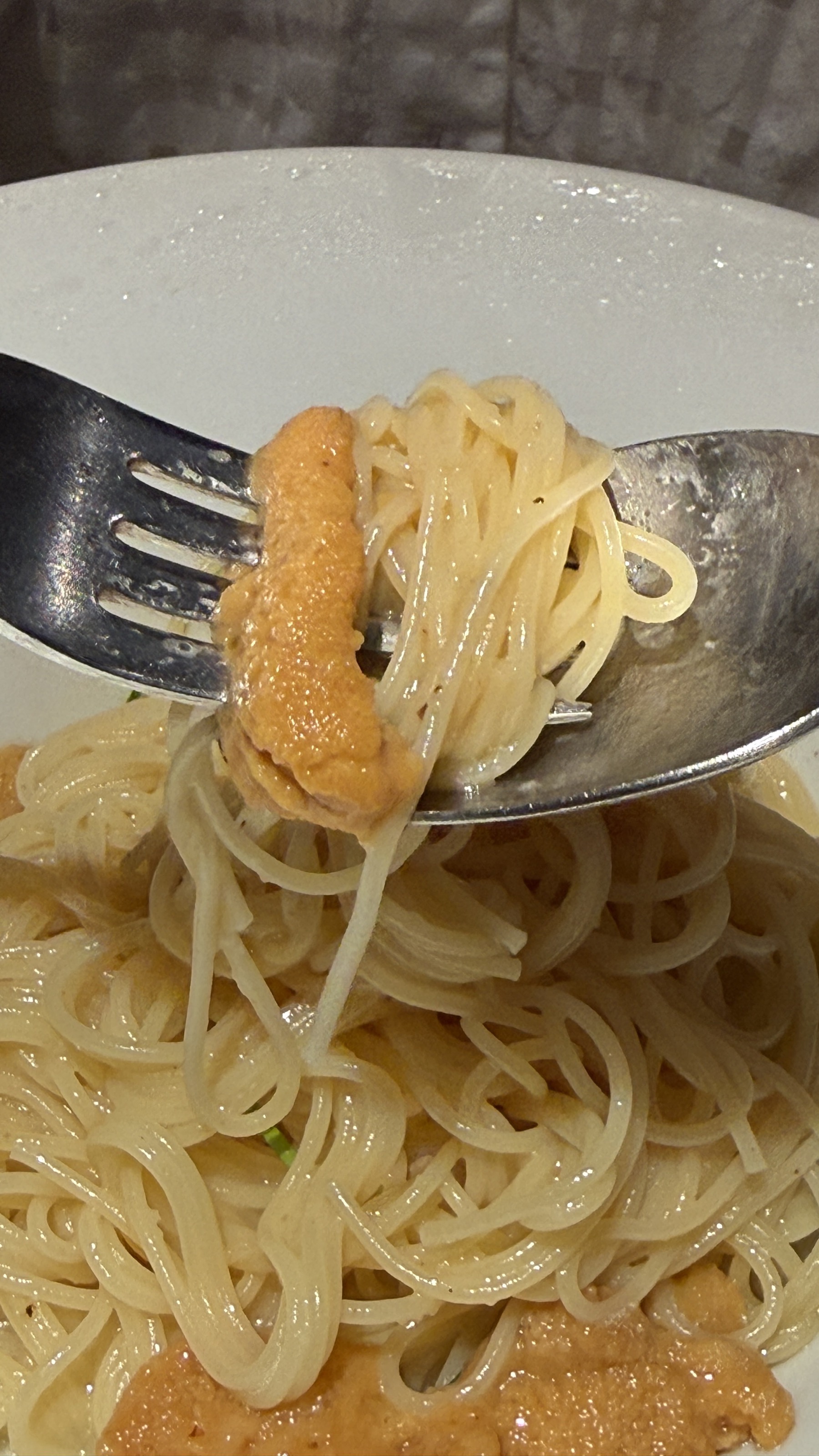 フォークで持ち上げたウニスパ。細麺にウニがひと粒のっている接写