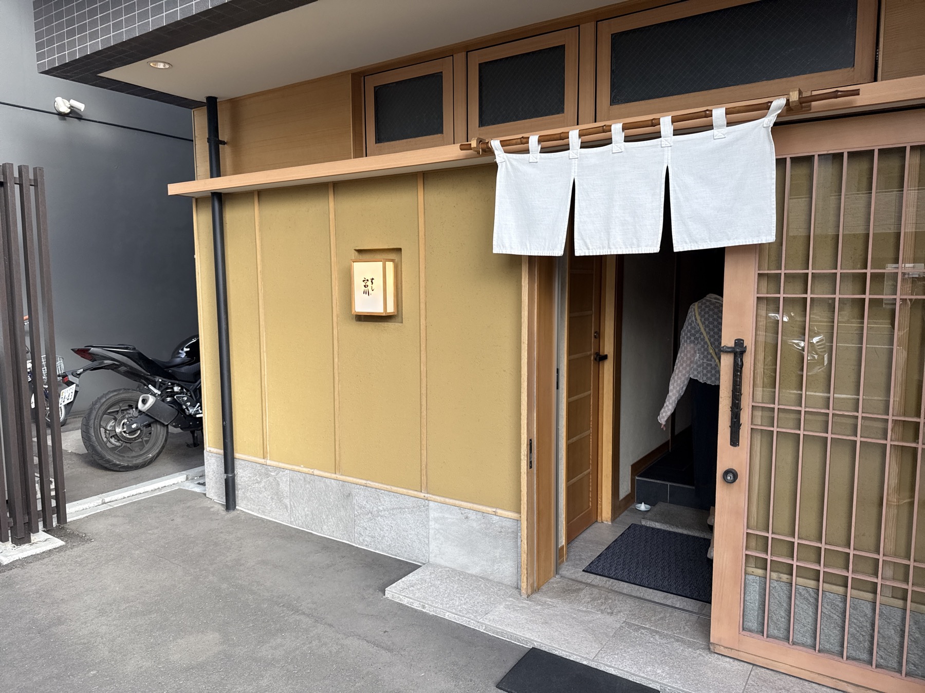 札幌・円山公園駅から徒歩数分、ミシュラン三つ星寿司店「すし宮川」の店構え。すっきりとした和の入口に白い暖簾、控えめな店名プレート