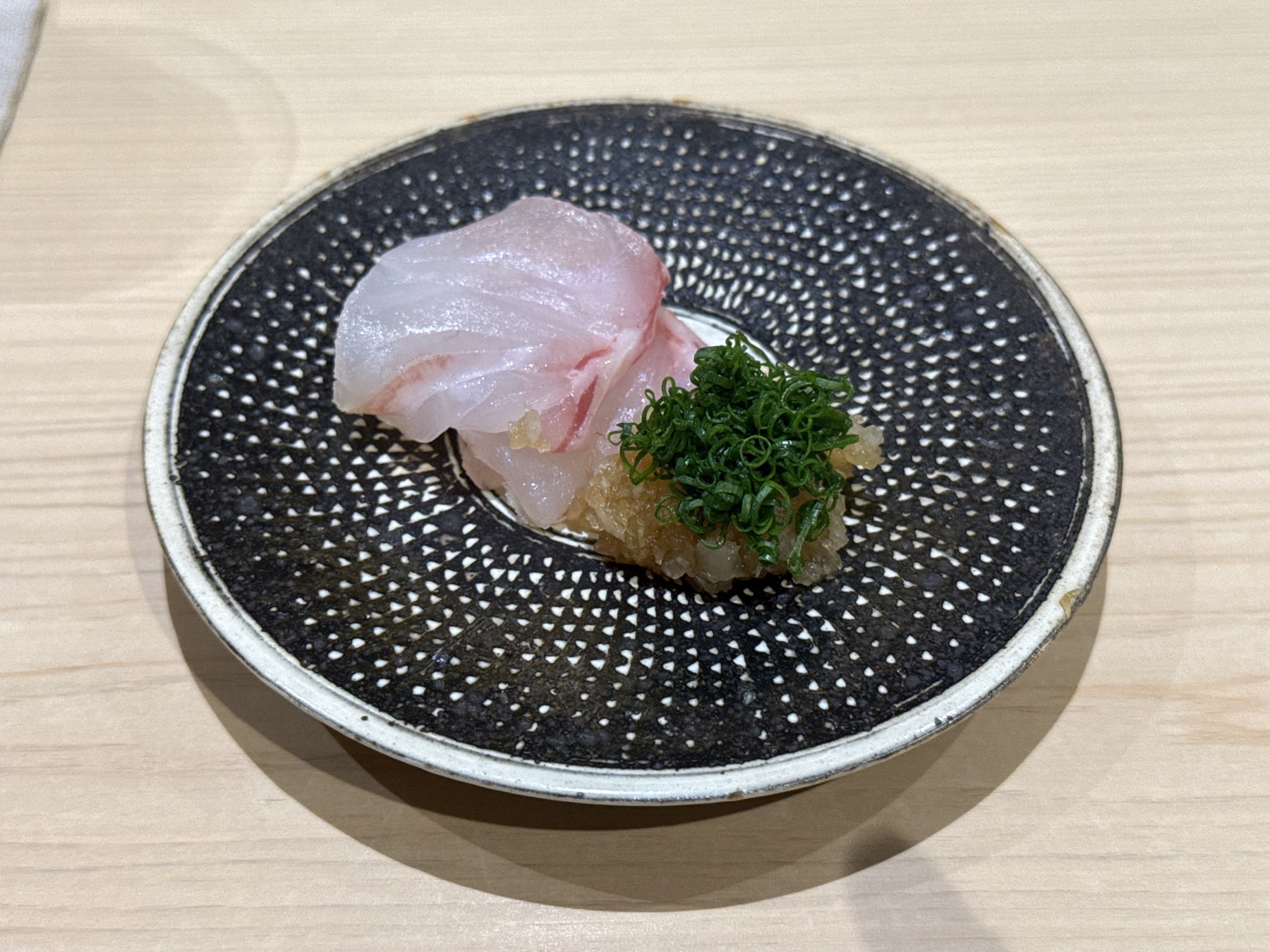 白身の刺身を大根おろしと青ねぎで仕立てた一品。器の細かなドット文様が料理を引き立てる