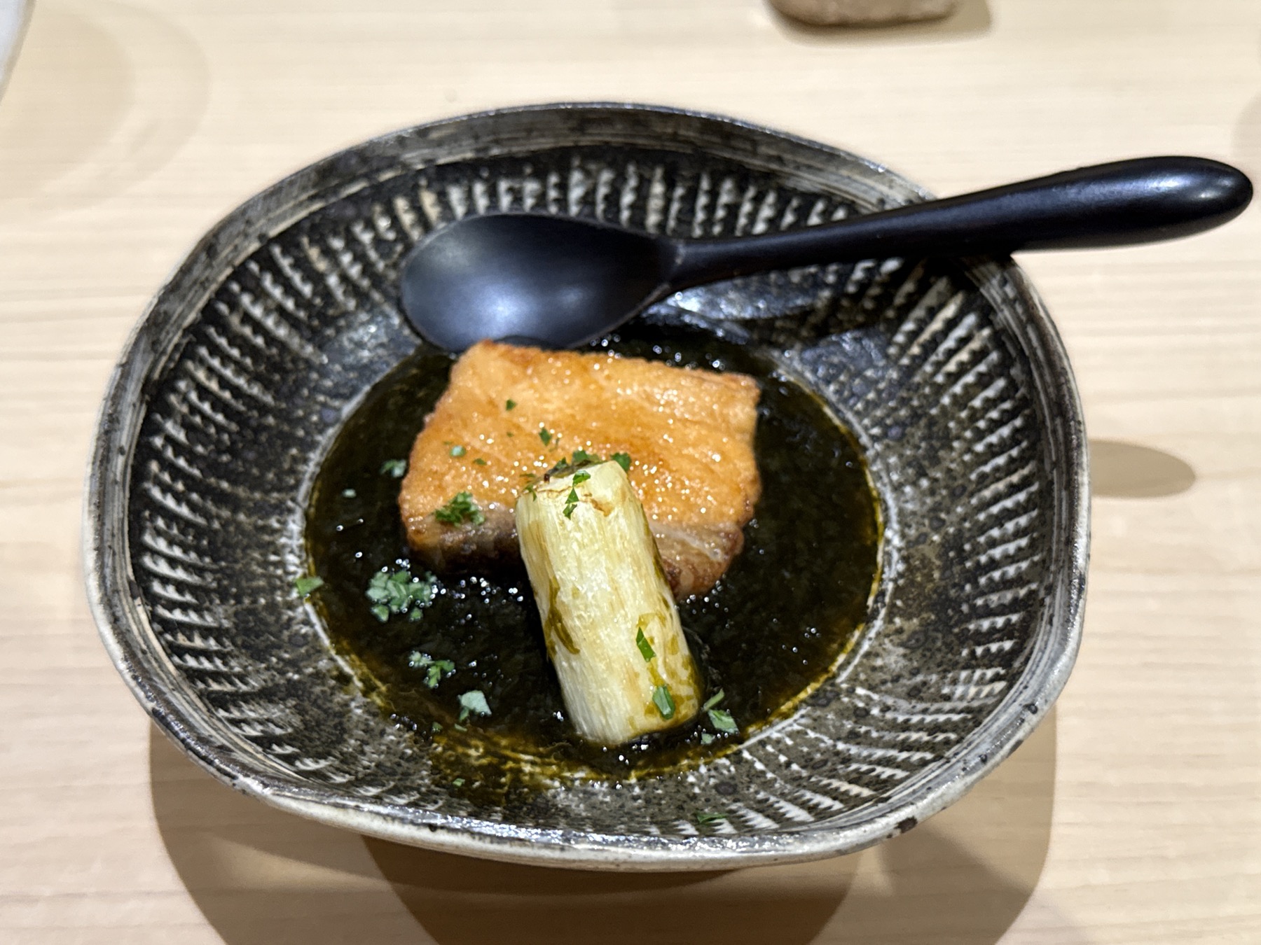 出汁が張られた揚げ物の一品。スプーンが添えられ、最後の一滴まで楽しませてくれる