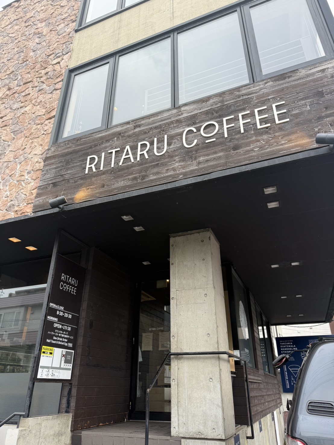 木の看板に「RITARU COFFEE」と掲げられたリタルコーヒーの店舗外観。コンクリートと木を組み合わせた落ち着いた佇まい