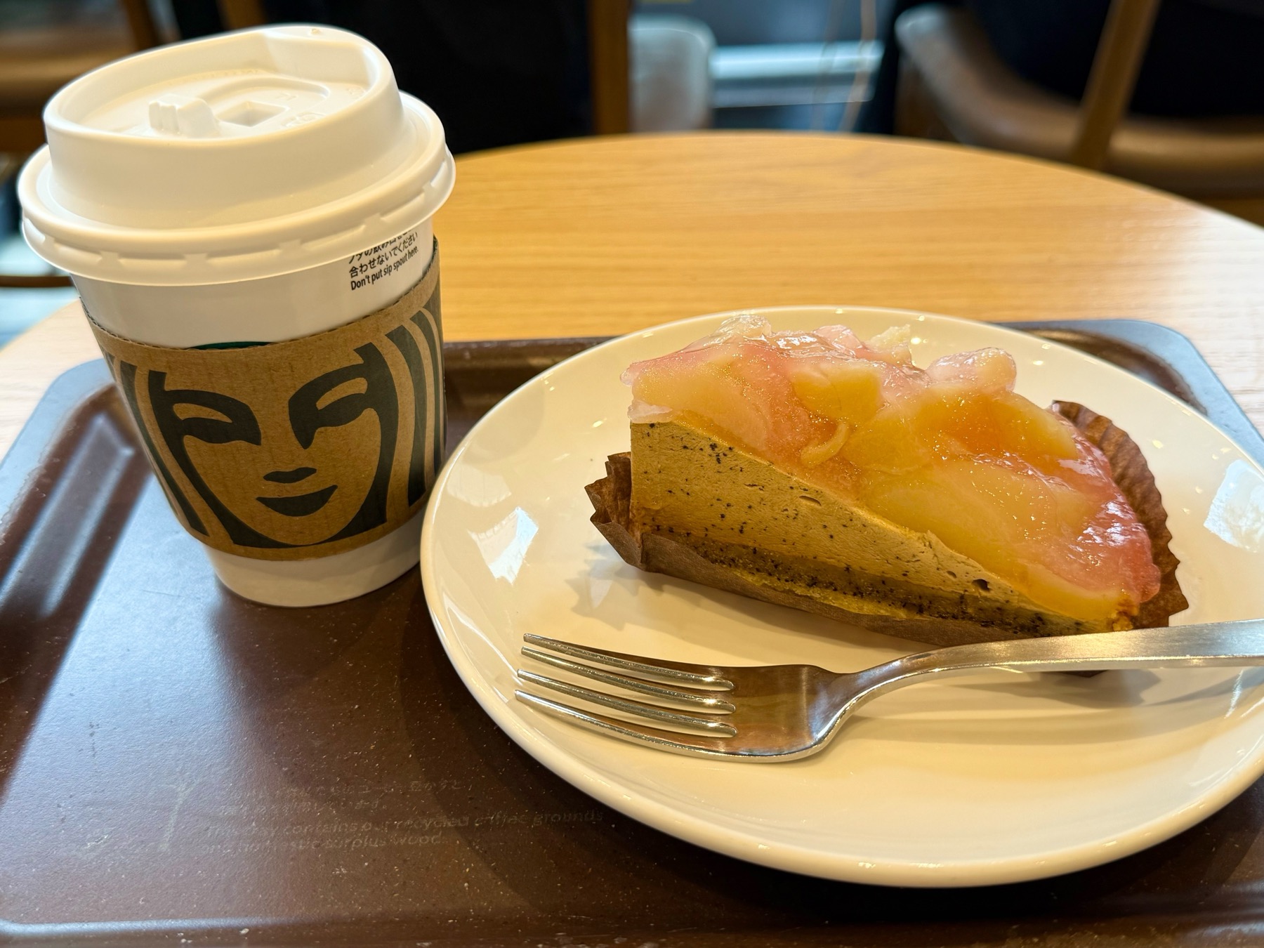 スターバックスの白桃＆アールグレイタルトと、シアトルコーヒーのカップ。トレイに並んでいる