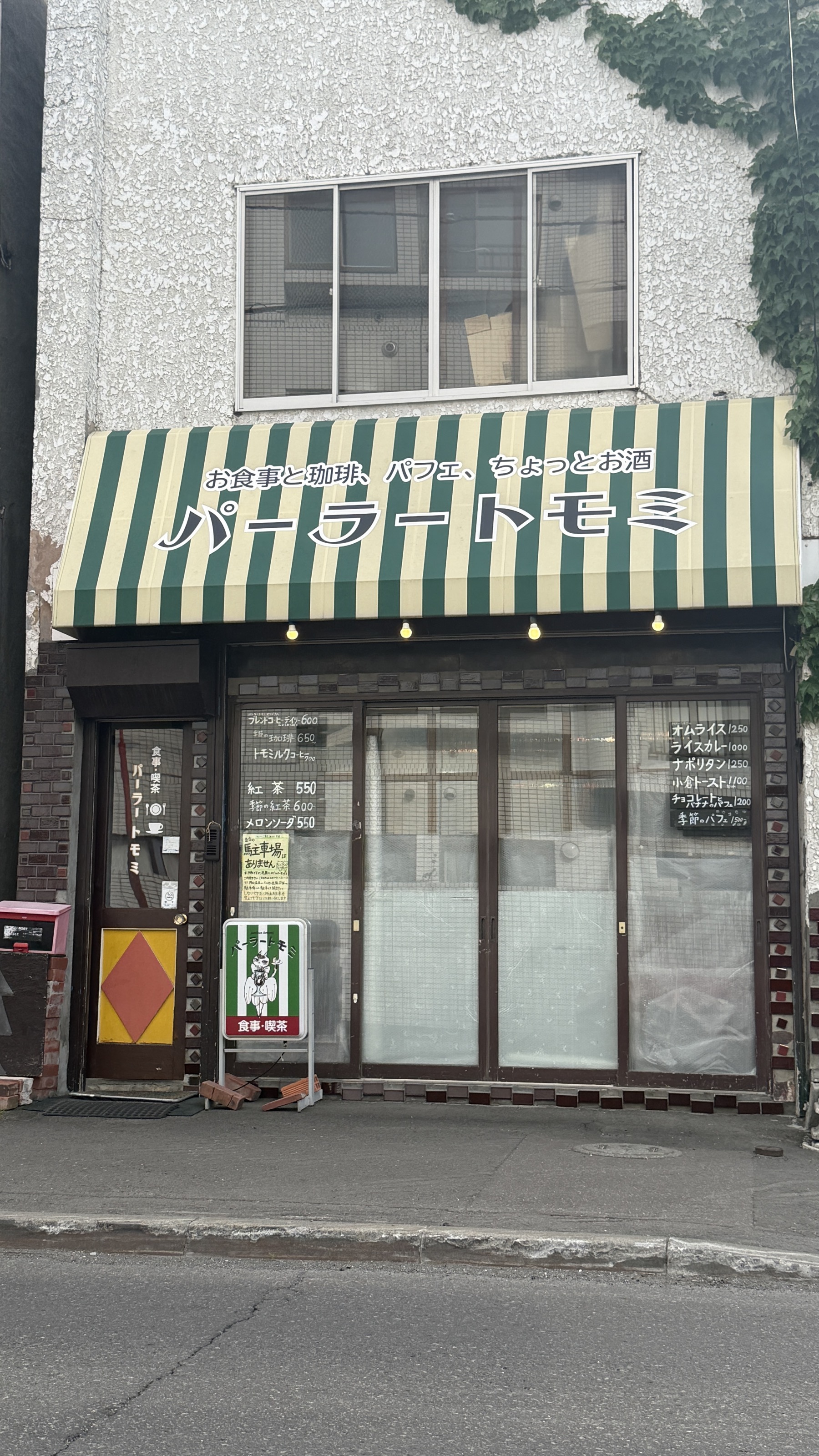 パーラートモミの外観。縦アングル。スタンド看板に「食事・珈琲」の文字