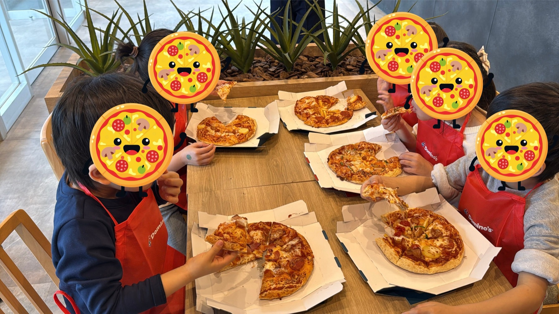 店内のテーブルを囲んで、自分たちが作ったピザを食べる子どもたち。それぞれの前に違う見た目のピザが並んでいる