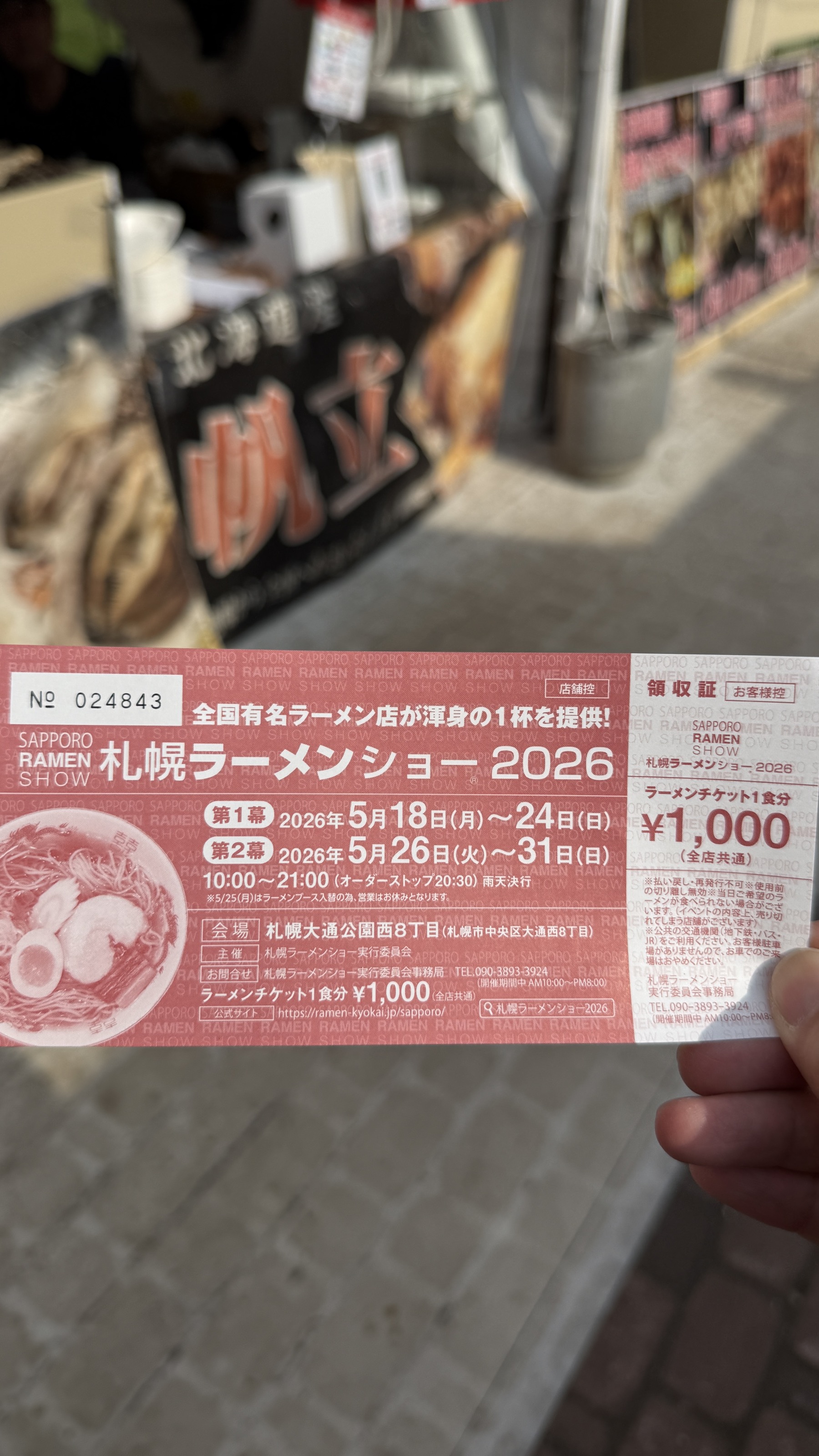 札幌ラーメンショー2026の食券。赤と白のデザインで、価格1,000円、第1幕5/18-24、第2幕5/26-31、会場「札幌大通公園西8丁目」、営業時間10:00-21:00と記載