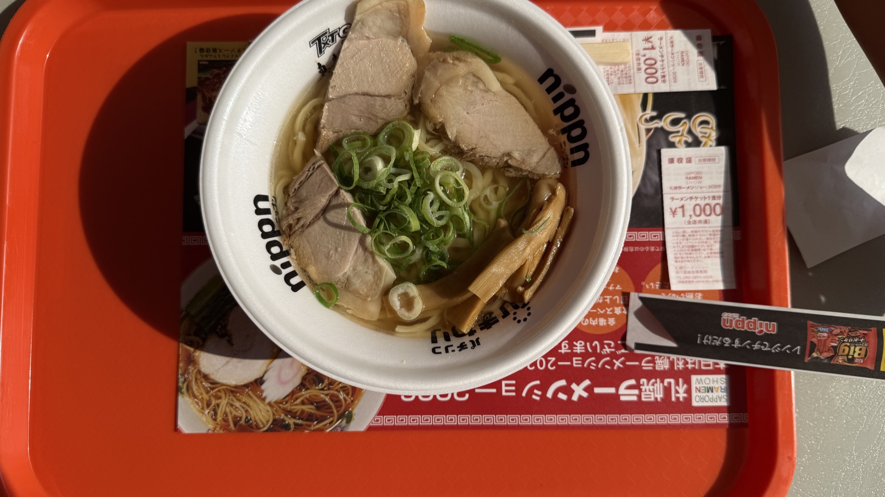 会津山塩 極上しおラーメンを上から撮影。透き通った塩スープに、ぶ厚いチャーシュー2枚、刻みネギ、メンマ。お盆の上には食券