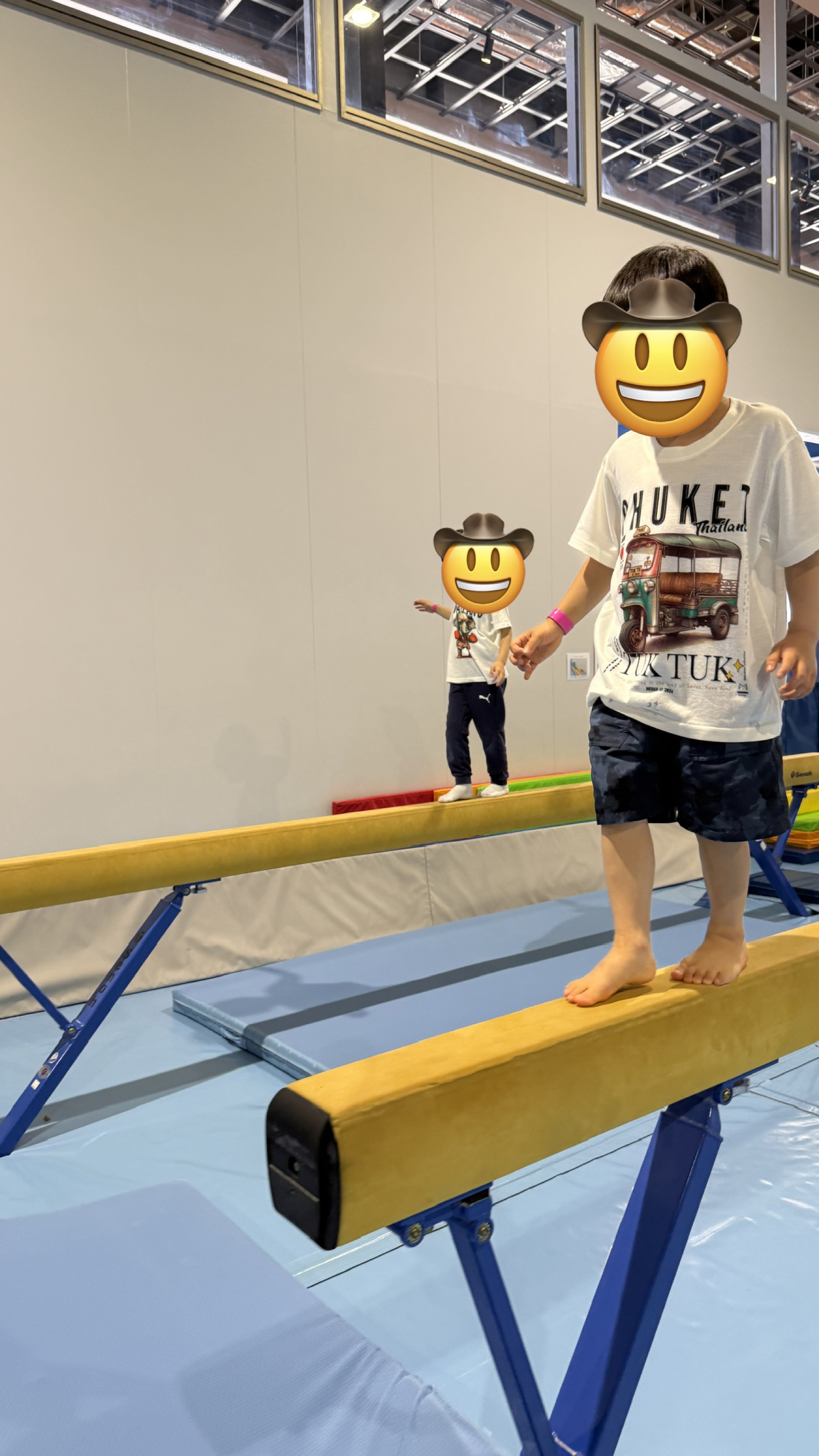 長男と次男が平均台に乗って遊んでいる様子。プライバシー保護のため、子どもの顔は絵文字で隠してあります