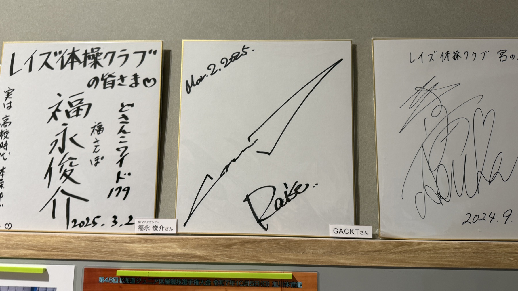 レイズ体操クラブ宮の沢店の入り口に飾られたサイン色紙。中央にGACKTさんのサイン（Mar 2 2025）、両脇に他のサイン色紙が並んでいる